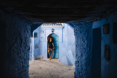 Portrait of smiling woman standing at building seen through archway 