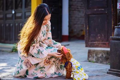 Full length of woman sitting outside building