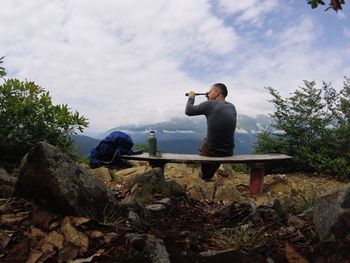 Man looking through binoculars against sky