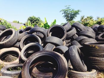 Stacked tires on field against clear sky