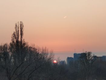 High angle view of silhouette trees and buildings against sky at sunset