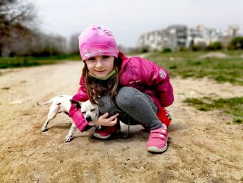 Portrait of girl with puppy on field