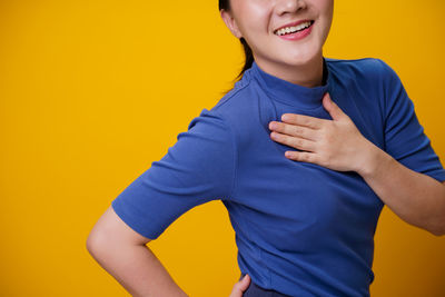 Midsection of woman standing against yellow background