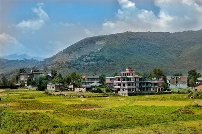 Scenic view of houses by mountains against sky