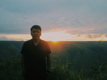 Man standing on field against sky during sunset
