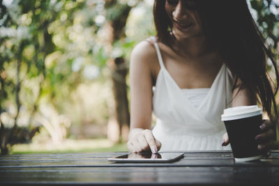 Midsection of woman using digital tablet at table