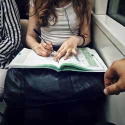 Midsection of woman studying in train