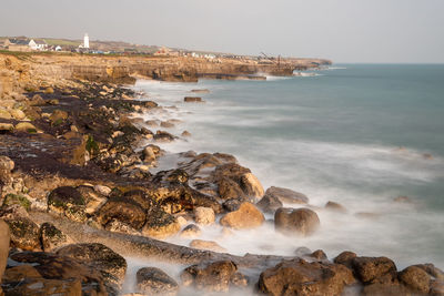 Long exposure of the tide washing over the rocks on the beach at portland bill in dorset