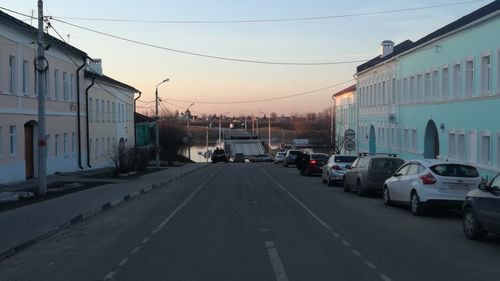 Cars on road by buildings in city against sky