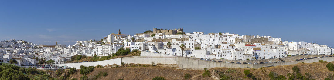 Panoramic view of buildings in city against clear blue sky