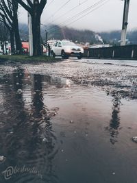 Wet street in city against sky