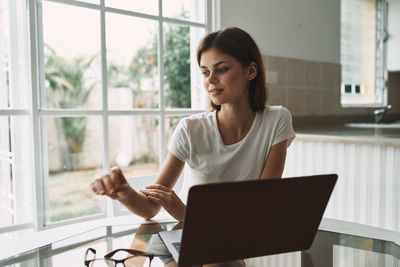 Young woman using mobile phone while sitting on table