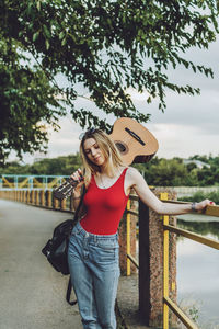 Beautiful blonde girl with guitar outdoor portrait. young woman playing guitar in city street