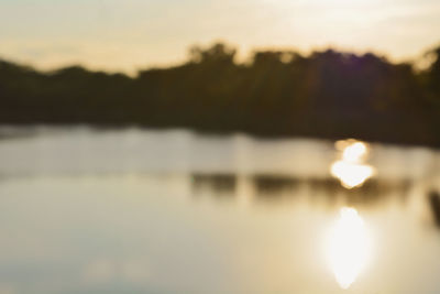 Reflection of silhouette trees on lake against sky during sunset