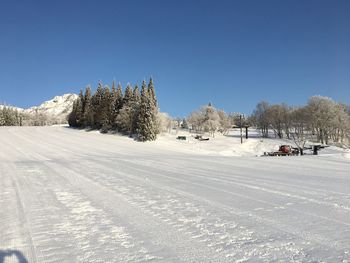 Snow covered land against clear sky