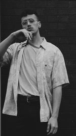 Portrait of young man with cigarette standing against wall