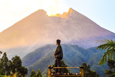 Man standing at observation point against mountain during sunset