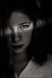 Close-up portrait of serious teenage girl against black background