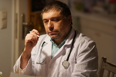 Thoughtful mature doctor with pen working in hospital