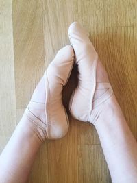 Low section of ballet dancer sitting on hardwood floor