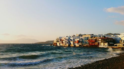 Scenic view of sea by buildings against sky