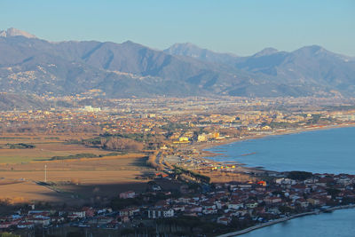 Aerial view of townscape by sea against sky