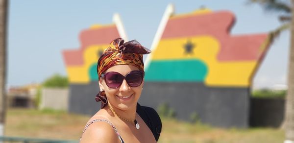 Side view portrait of smiling woman wearing sunglasses against ghanaian flag
