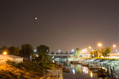 Illuminated canal by city against sky at night