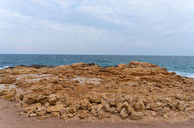 Scenic view of rocks on beach against sky
