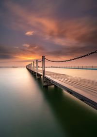 Bridge over sea against sky during sunset