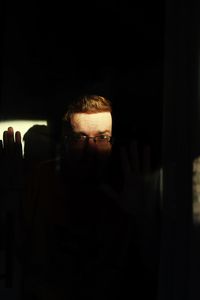 Portrait of young man sitting in dark room