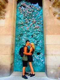 Full length of young woman with tattoo on wall