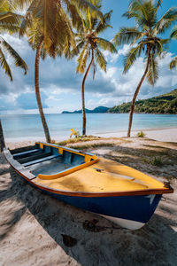 Boat moored at beach against palm trees