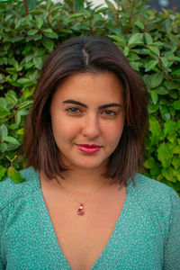 Close-up portrait of beautiful young woman by plants