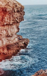 Rock formation in sea against sky