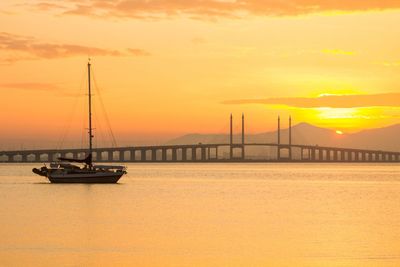 Silhouette boat in sea against sunset sky