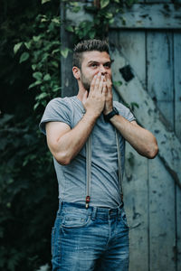 Portrait of young man holding camera while standing outdoors