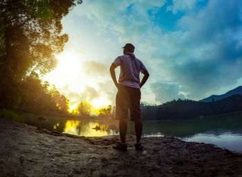 Man standing by tree against sky during sunset