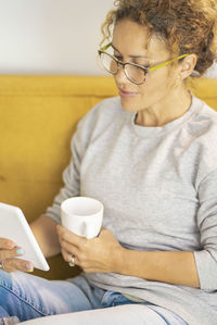 Young woman using phone while sitting on sofa at home