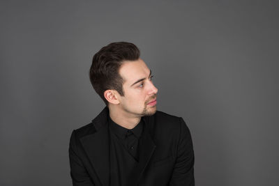 Young man looking away against black background