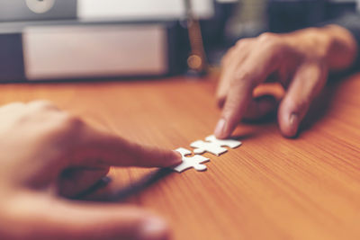 Close-up of hands playing jigsaw puzzle on table