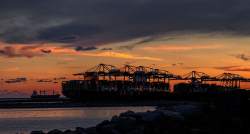 Silhouette pier on beach against sky during sunset