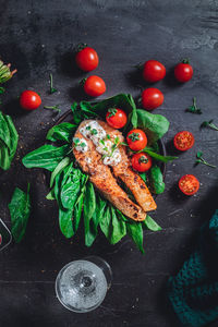 A plate with fresh green raw spinach and fried wild salmon, tomatoes and cream cheese sauce 