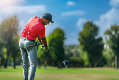 Pro golfer in a golf swing, using a driver golf club, rear view