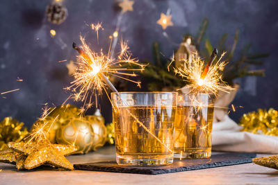 Burning sparklers in glasses with cocktails on the christmas table. gold palette