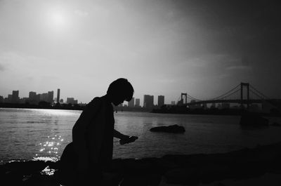 Silhouette of man with suspension bridge in city