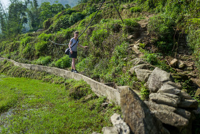 Full length of woman walking on retaining wall