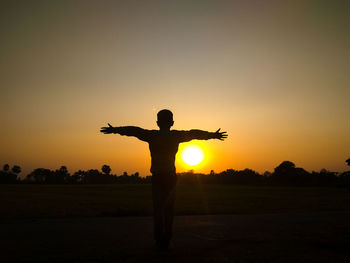 Silhouette man standing on field against sky during sunset