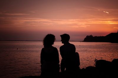 Silhouette couple at beach against sky during sunset