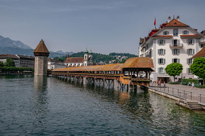 Bridge over river by buildings against sky